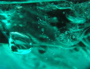 Bolle di gas incluse in vetro artificiale verde al microscopio